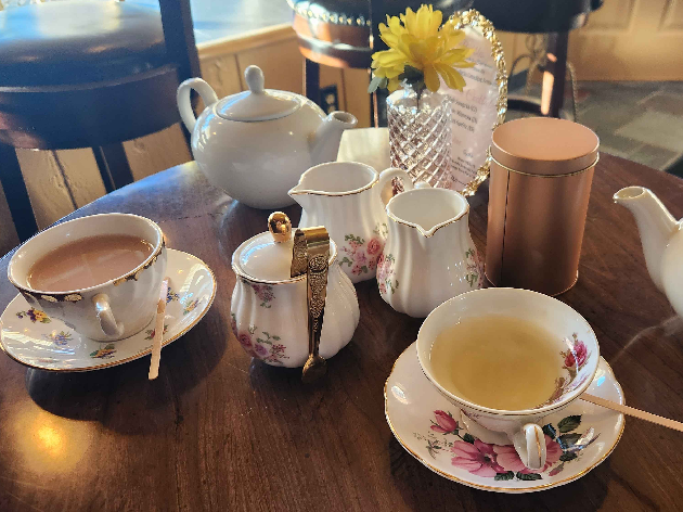 A pleasant spread of teacups and a couple teapots.