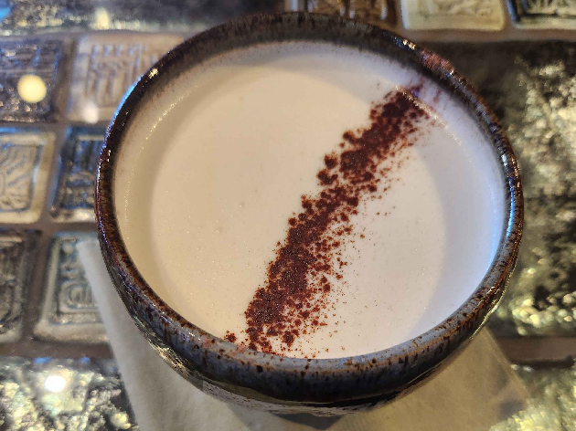 A mug with a foamed white beverage with a line of powdered cocoa on top.